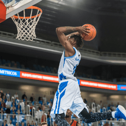 Basketball player dunking a ball in a stadium