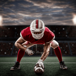 Football player in a three-point stance in a stadium