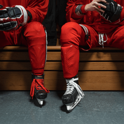 Close-up of hockey players' skates on a locker room bench
