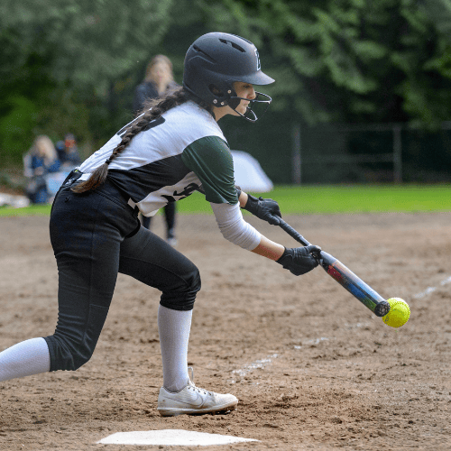 Female softball player in batting stance making contact with the ball
